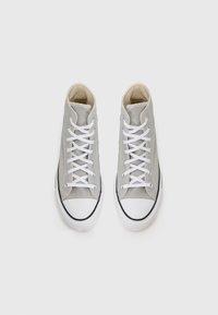 High-top shoes in light gray canvas with white laces and rubber soles. Features a white toe cap with a black trim.
