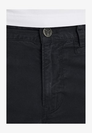 Jeans neri con una texture liscia, design classico a cinque tasche, chiusura con bottone in metallo e cuciture a contrasto lungo le cuciture.