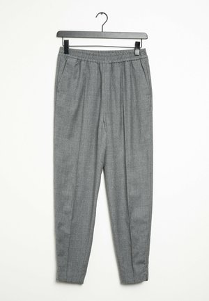 Harmaat joustavat vyötäröhousut, joissa on sivutaskut ja kapenevat lahkeet, ripustettu mustaan henkariin valkoista taustaa vasten.