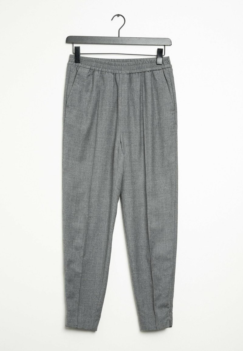 Pantalon gris à taille élastique, avec poches latérales et jambes fuselées, suspendu sur un cintre noir sur fond blanc.