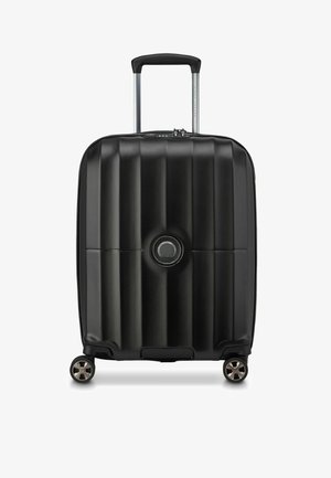 Maleta rígida negra con estrías verticales, mango retráctil y cuatro ruedas. Presenta un acento de mango circular en la parte frontal.