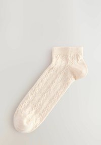 Gebreide enkel sok in lichtcrème, met een textuur kabelpatroon, geribde manchet en een gladde teennaad voor comfort. Katoenmengsel.