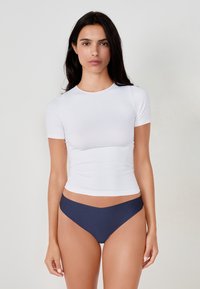 Weißes, kurzärmliges Top mit taillierter Passform, kombiniert mit navyblauen Bikinihosen. Glattes Gewebe mit leichtem Glanz und Rundhalsausschnitt.