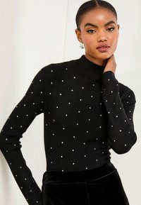 Czarny, ribbed sweter z długim rękawem i wysokim kołnierzem, z rozproszonymi srebrnymi kropkami jako akcentami. Miękka faktura, dopasowany krój.