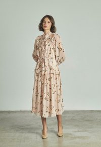 Vestido de estampado floral en suave tela rosada, con volantes, un escote alto con un lazo y una falda fluida con capas.