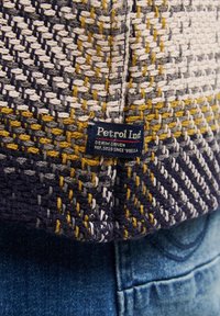 Tessuto con motivo nelle tonalità di blu navy, grigio, giallo e bianco. Presenta un'etichetta con le scritte "Petrol Ind" e i tag "DENIM DRIVEN" attaccati.
