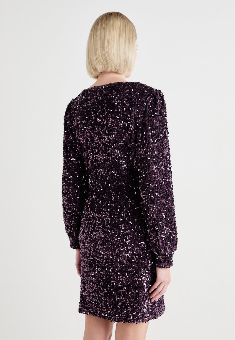 Fioletowa sukienka z cekinami, z długimi rękawami, o dopasowanym kroju i teksturowanej powierzchni, prezentująca błyszczący efekt dzięki cekinom.