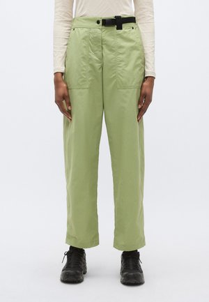 Helerohelised, lahtise lõikega püksid, millel on vöökohal vöö, kaks esitaskut, lame esikülg ja pehme tekstuur, kombineeritud mustade spordijalatsitega.