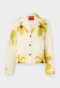 Cropped jacket in soft fabric, cream with yellow floral print, notched collar, button front, and long sleeves. Accented with dark buttons.