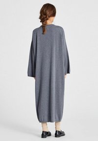 Dolga, ohlapna siva pletena obleka z širokimi rokavi in zaobljenim izrezom. Na dnu ima rebrast rob.