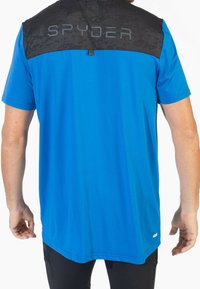 Camisa de manga corta azul con sección superior de camuflaje negro y logo de SPYDER. Tejido suave con corte recto y dobladillo trasero ligeramente más largo.