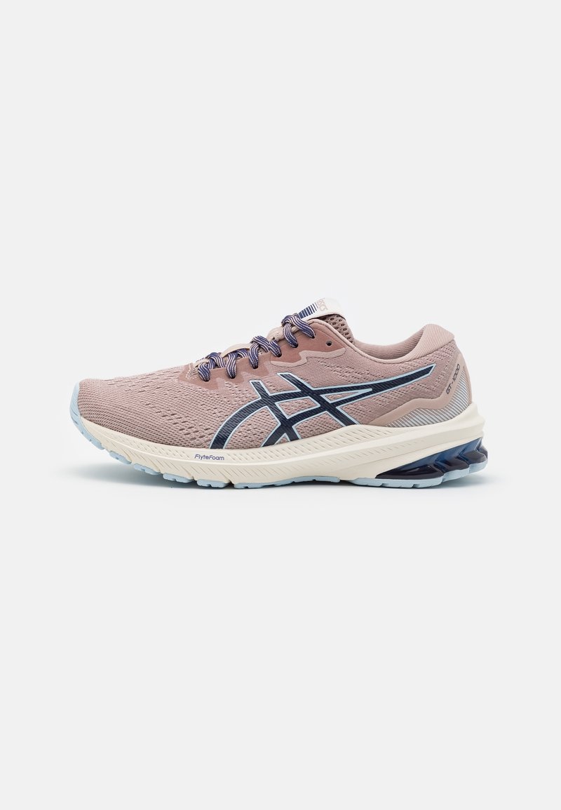 Chaussure de course mauve clair avec logo marine, semelle amortissante et support du talon accentué de bleu, conçue pour la performance athlétique.