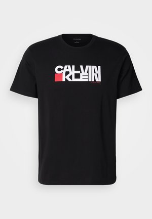 Czarna bawełniana koszulka z krótkim rękawem z wyraźnym białym i czerwonym logo "CALVIN KLEIN" na piersi. Klasyczny krój z okrągłym dekoltem.