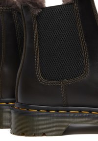 Stivali alla caviglia in pelle marrone con pannelli elastici neri testurizzati, cuciture gialle e suola in gomma con un design rigato.