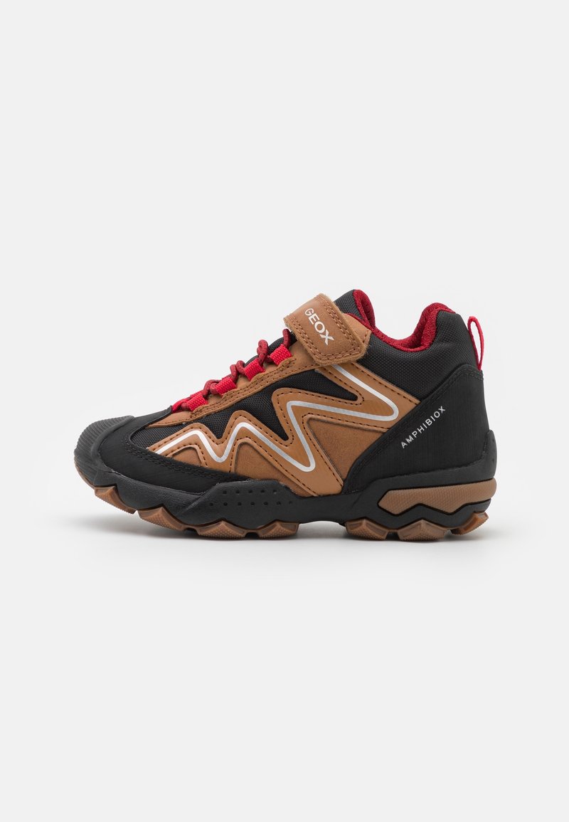 Chaussure de randonnée noire et marron avec des lacets rouges, dotée d'un col matelassé, d'une semelle en caoutchouc texturée et d'un motif en zigzag sur les côtés. Logo de la marque visible.