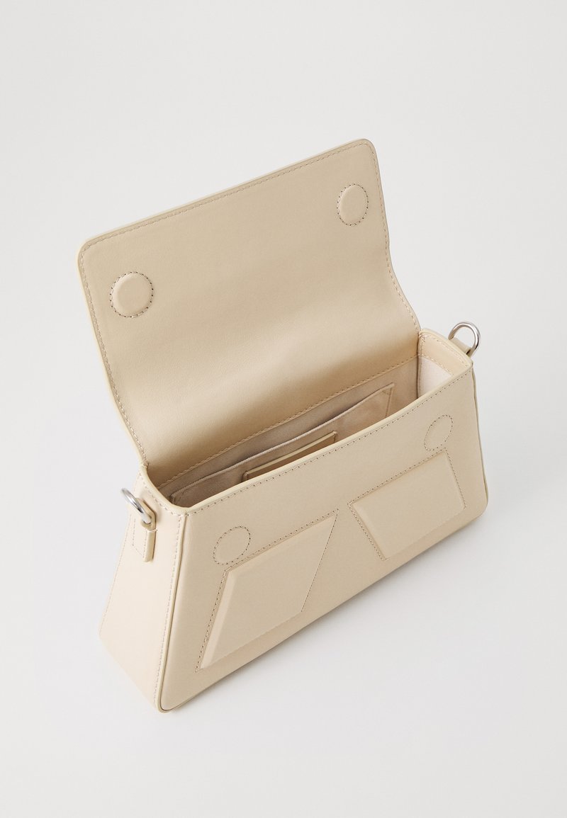 Beige Lederhandtasche mit einer schrägen Form, magnetischem Verschluss, zwei Außentaschen und glatter Textur. Innen ist ein Kartenfach vorhanden.