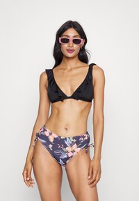 Svart bikiniöverdel med volanger, kombinerad med högmidjade underdelar i blommönster med blå och rosa blommor, justerbara sidoknytningar.