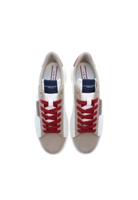 Beige en witte sneakers met een suede afwerking, voorzien van rode veters en accenten, en een blauwe logotag op de tong. Klassiek laag ontwerp.