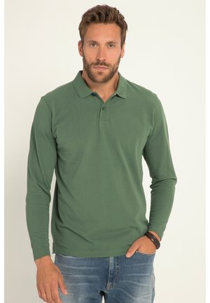Langærmet polo skjorte i mørkegrønt stof, med klassisk krave, tre-knaps placket og en tætsiddende pasform. Bæres med blå jeans.