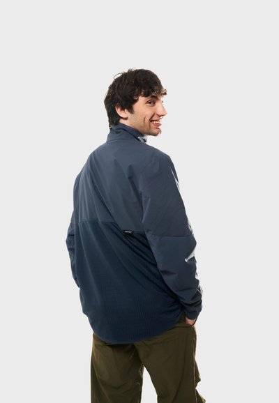 Marinblå vindtät jacka med en texturerad nedre panel, hög krage och avslappnad passform. Har en logotags på baksidan.