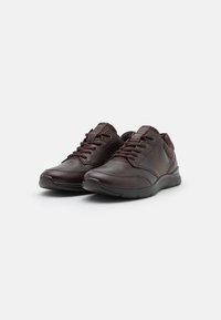 Braune Leder-Sneaker mit Schnürdesign, strukturierten Akzenten und seitlichen Perforationen für Atmungsaktivität, mit einer robusten Gummisohle.