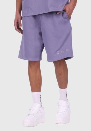 Lichtpaarse shorts met een elastische tailleband en zijzakken, met geborduurde tekst "Dropsize". Gemaakt met witte sneakers en sokken.