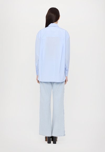 Light blue long-sleeve shirt with a collared neck and a straight cut, paired with light blue wide-leg jeans and black platform heels.