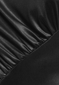 Schwarzer Stoff mit glatter, glänzender Textur, der auf einer Seite gerafft ist und auf der anderen Seite ein elegantes Finish aufweist, was einen Kontrast in der Oberfläche erzeugt.