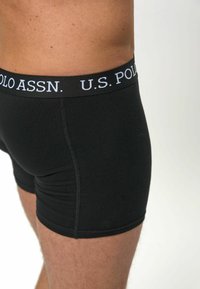Schwarze Boxershorts mit einem weichen Bund, der mit dem weißen Logo "U.S. POLO ASSN." versehen ist. Der Stoff wirkt glatt und dehnbar.