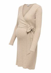 Robe de maternité beige côtelée avec manches longues, design portefeuille et détail de nœud sur le côté. Texture douce et silhouette ajustée.