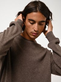 Bruine gebreide trui met een relaxed fit, zachte textuur en geribbelde manchetten. Het ontwerp heeft een ronde halslijn en standaard lange mouwen.