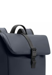 Zaino blu navy realizzato in tessuto impermeabile, con un risvolto e una tracolla nera regolabile con una fibbia in plastica.