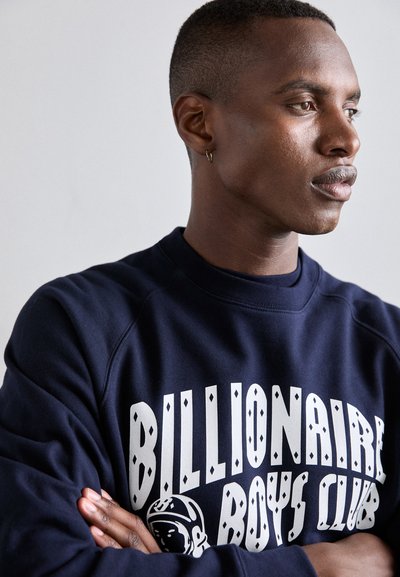Sweat-shirt bleu marine avec le texte et le logo "Billionaire Boys Club" en blanc ; présente un col côtelé et un tissu doux et texturé.