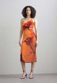 Rochie din satin portocalie, cu un model floral, un bretele, design ajustat și lungime midi. Sandale negre cu toc înalt.