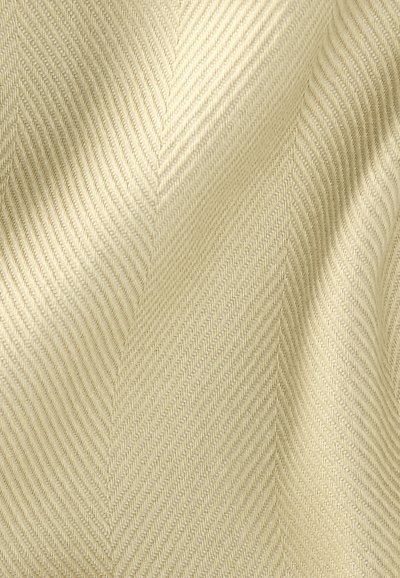 Ύφασμα σε κρεμ απόχρωση με διακριτικό μοτίβο ψαροκόκαλου και απαλά πτυχώσεις που δημιουργούν ήπιες σκιές και υφή.