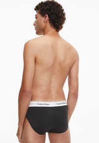 Slip in cotone nero con elastico bianco in vita che riporta il logo Calvin Klein. Il design presenta una forma classica da slip.