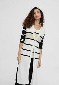 Cardigan lungo realizzato in tessuto leggero, con righe orizzontali blu navy e beige, dotato di chiusura con bottoni sulla parte anteriore e maniche a tre quarti.