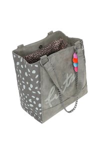 Sac fourre-tout gris en matériau doux avec des pois blancs, une doublure à pois roses, des anses en chaîne et en tissu, et un accent de pompon coloré.