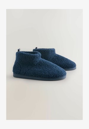 Chaussons chevilles en polaire bleu marine avec une texture douce, un bout arrondi et une semelle plate. Comprennent un col court replié et un onglet pour tirer.