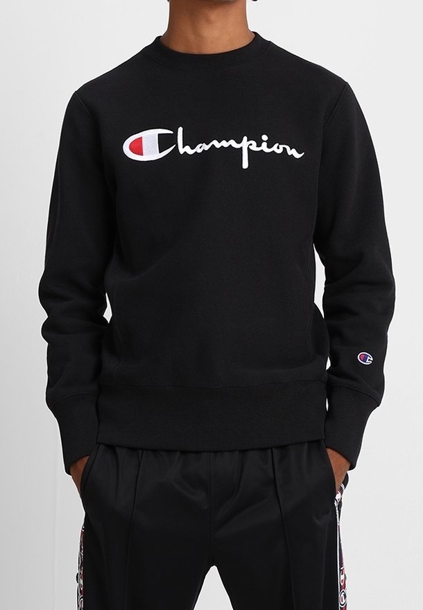 Felpa nera con colletto rotondo, con logo "Champion" ricamato in bianco. Texture liscia e polsini e orlo a coste.