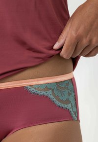 Bordeaux ondergoed met lichtgroenekante afwerking met bloempatronen en een perzikkleurige elastieken tailleband. Soepele stofstructuur.