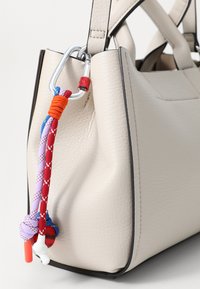 Sac à main en cuir beige avec des finitions noires, doté d'un clip carabiner et d'accents en corde nouée colorée. Texture lisse et forme structurée.