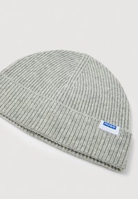 Szara dzianinowa czapka beanie z pionowym żebrowanym splotem i złożonym brzegiem. Posiada niebieską i białą metkę marki z boku.