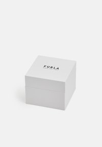 Valge pappkarp kaane ja musta trükiga, kus on brändinimi "FURLA" ja "SINCE 1927 ITALY". Lihtne, ruudukujuline disain.