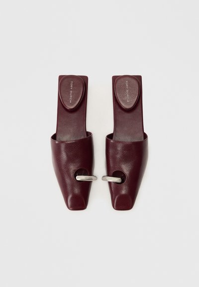 Burgundy leather slip-on shoes with a pointed toe, featuring a silver ring accent and a textured sole. Branding on the insole.