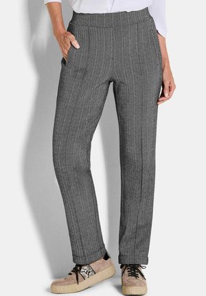Pantaloni grigi con motivo a spina di pesce, dotati di una cintura elastica, tasche laterali e design a gamba dritta, abbinati a sneakers beige e nere.