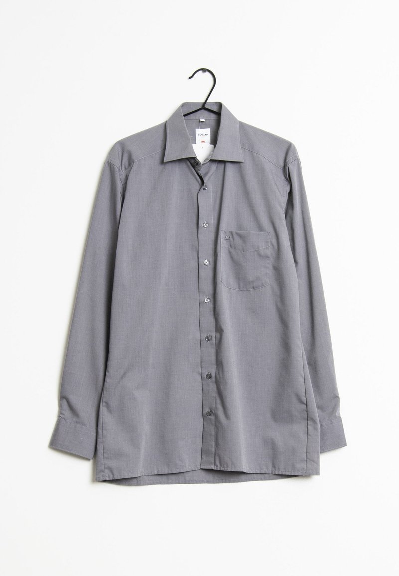 Chemise grise à manches longues, boutonnée, avec col et poche poitrine suspendue à un cintre noir sur fond blanc.