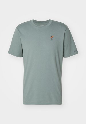T-shirt à manches courtes vert menthe en tissu doux. Présente un petit design brodé d'une personne avec une planche de surf orange sur la poitrine.