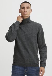 Tumehall villane kaelus-sweater, ribatud krae ja varrukatega, valmistatud tekstureeritud kudumaterjalist, kombineeritud siniste teksastega.