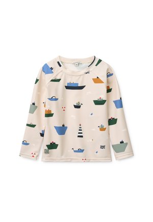 Béžová košeľa s dlhými rukávmi s farebnými potlačami lodí a majákov. Vyrobená z hladkej látky, s okrúhlym výstrihom a raglánovými rukávmi.